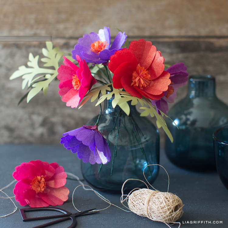 Tissue paper cosmos flowers in vase next to craft tools